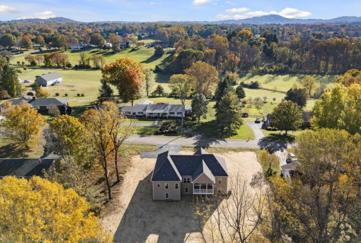 Aerial view of a newly constructed home surrounded by trees and a grassy field.