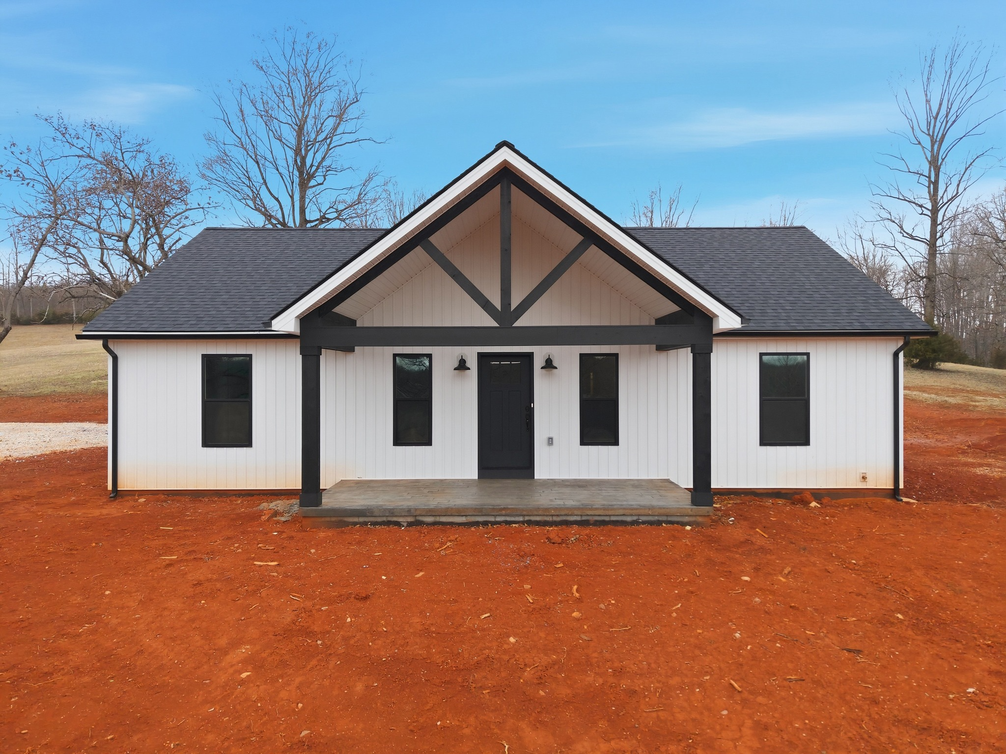 Newly constructed custom home on a cleared lot in Central Virginia, featuring a modern design with black accents, surrounded by red earth and trees.