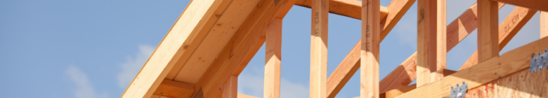 Wooden roof trusses against a blue sky.